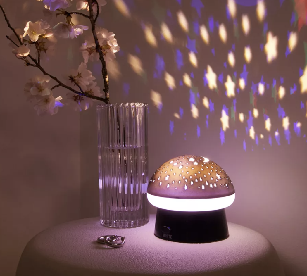 the mushroom lamp on a table lit up with stars on the wall