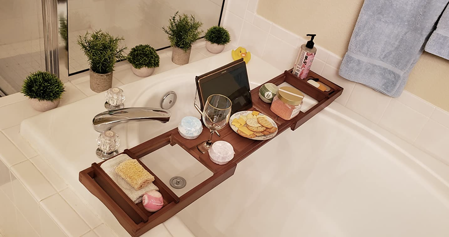 Reviewer image of a wooden bath caddy holding an iPad, cheese plate, candle, wine glass, bath salts