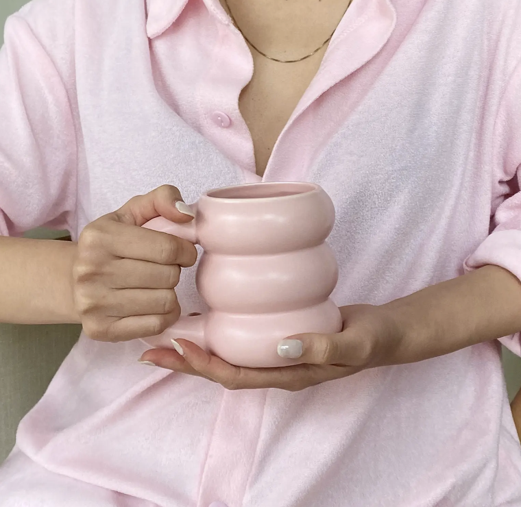 person holding the mug by the handle and resting it on their other hand