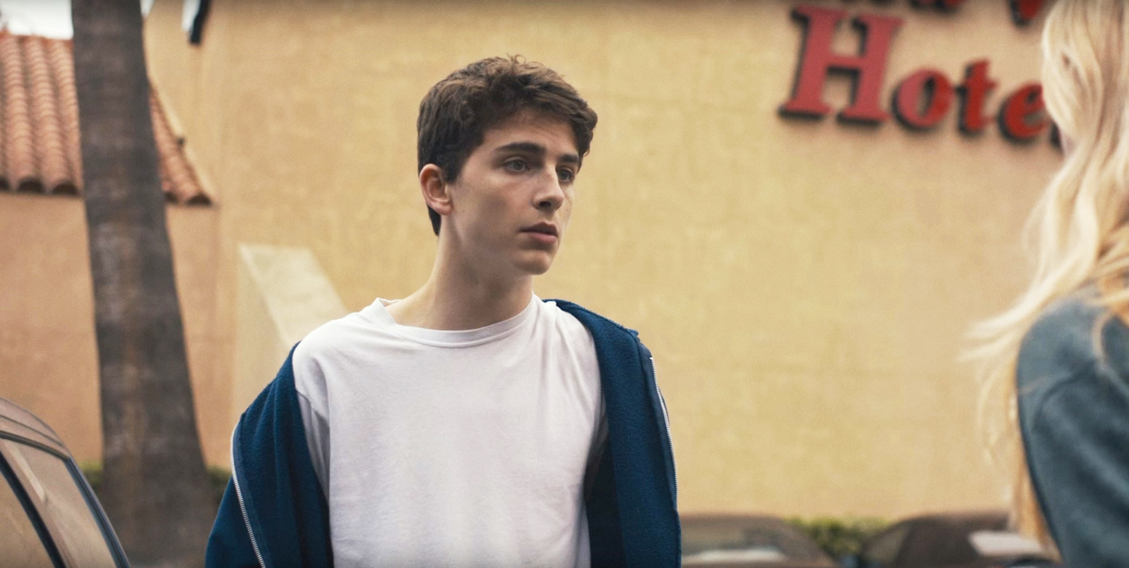 Timothee Chalamet stands outside of a hotel