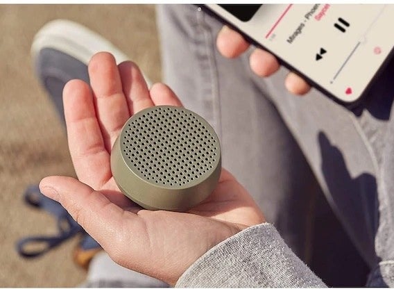 a person holding the speaker in the palm of their hand