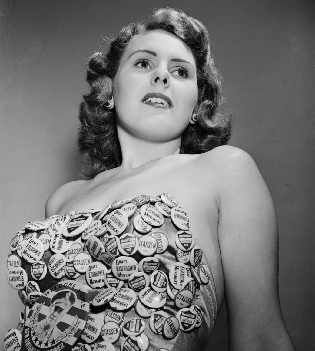 A woman looking into the distance over the camera wears a multitude of campaign pins fixed to her bathing suit that read &quot;draft Eisenhower movement&quot; and the name &quot;Stassen&quot;