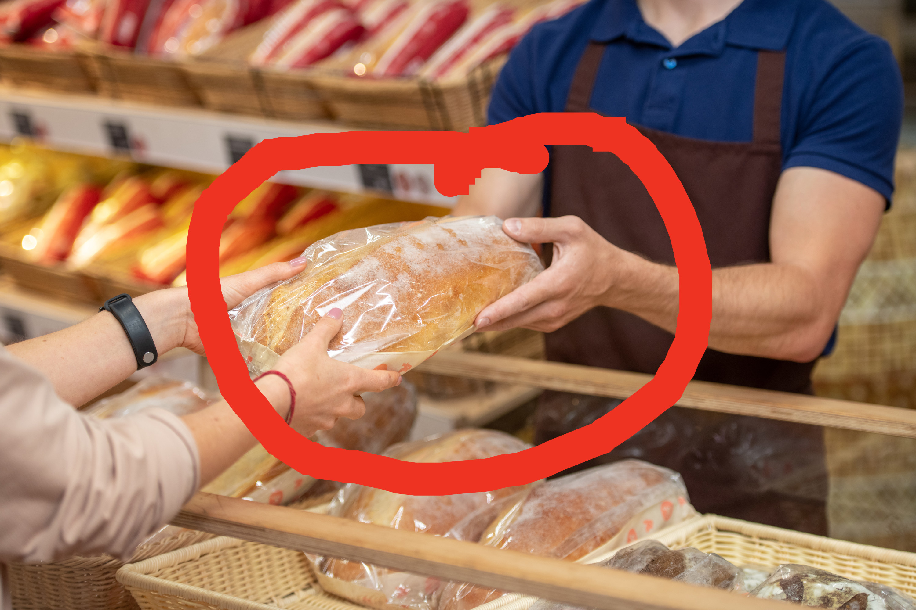 grocery store bakery employee handing a loaf of bread to a customer