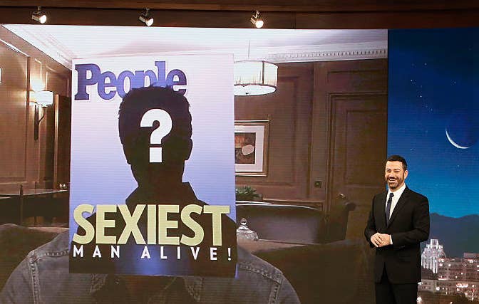 Jimmy Kimmel standing by a screen with a People magazine cover showing a question mark above &quot;Sexiest Man Alive!&quot;