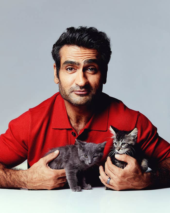 Kumail looking at the camera as he holds two cats