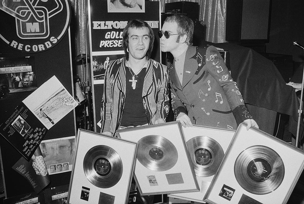 Taupin and John holding gold record plaques