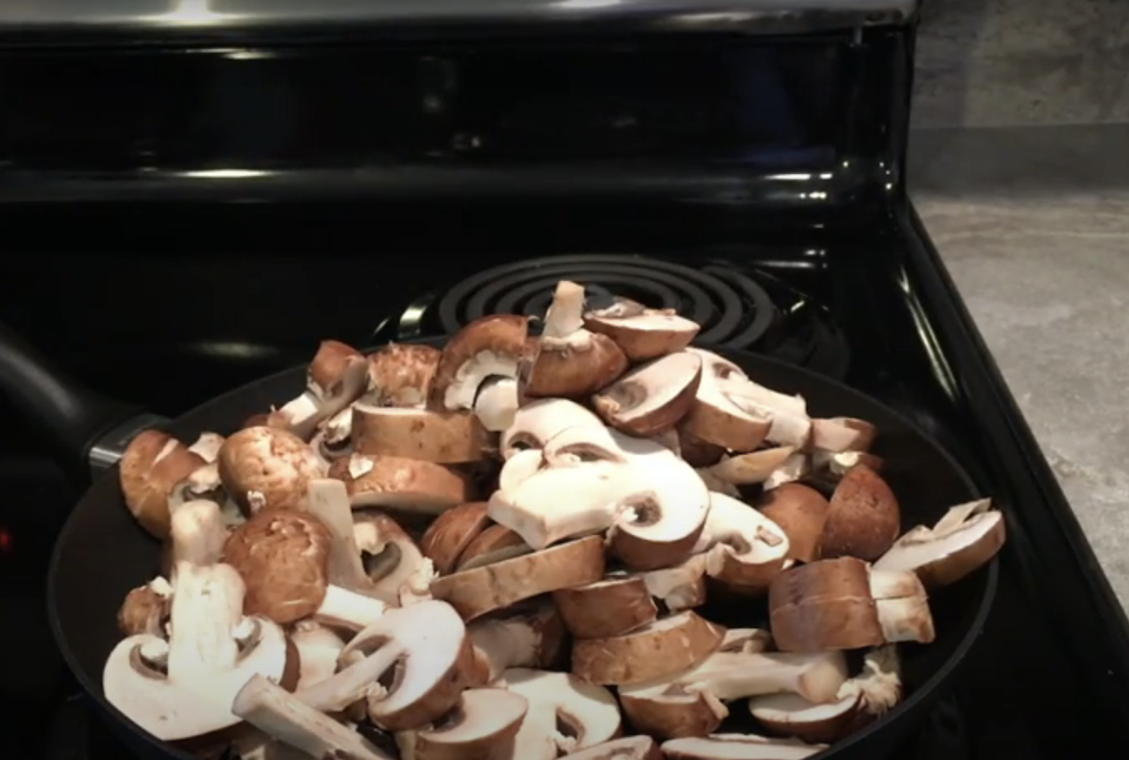 skillet with lots of uncooked mushrooms in it