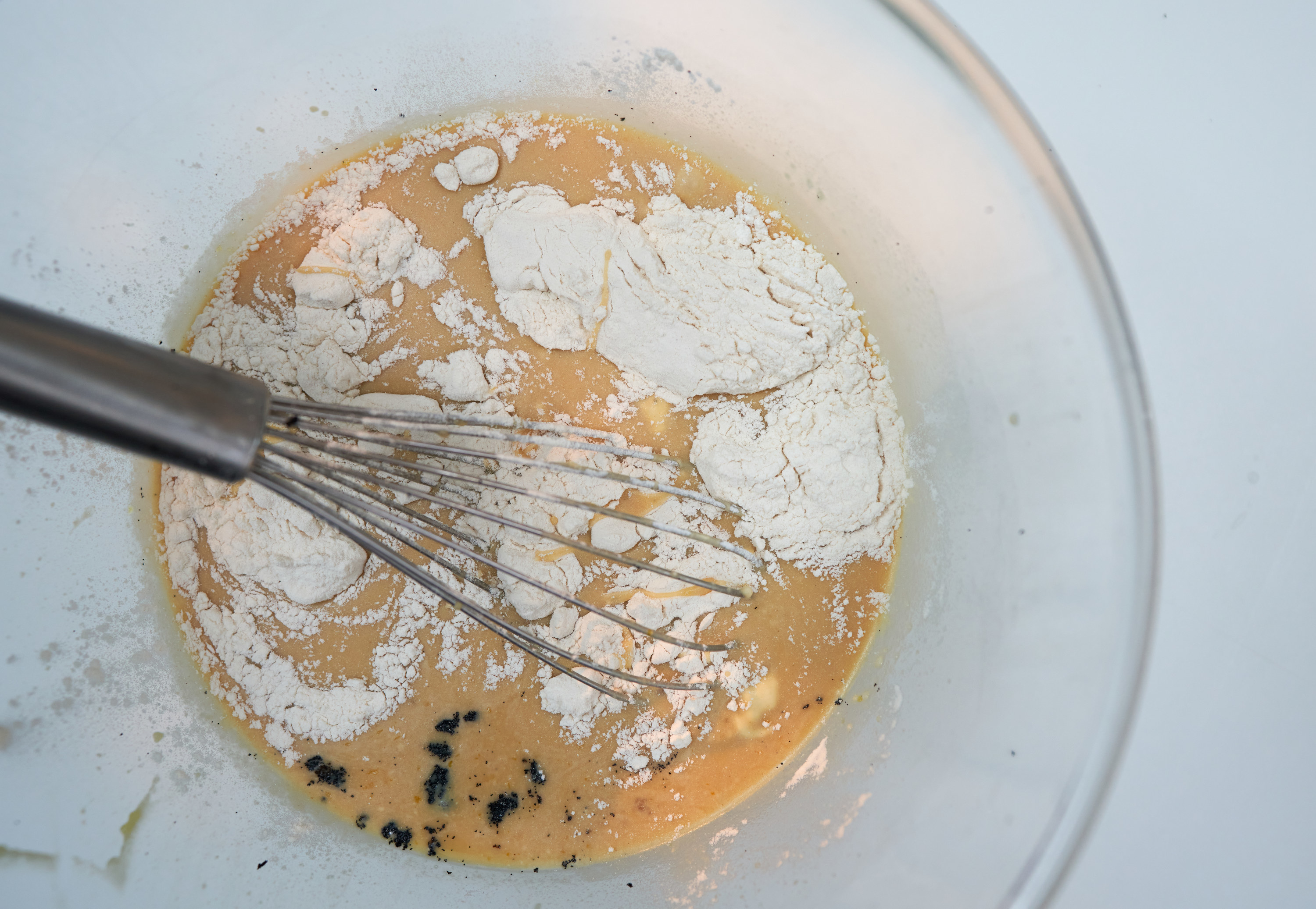 whisking flour into wet ingredients in a glass bowl
