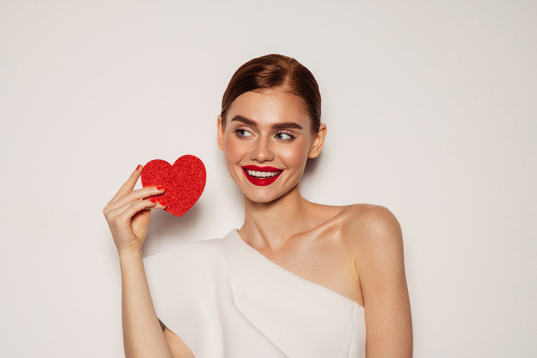 A woman smiling and holding a paper heart