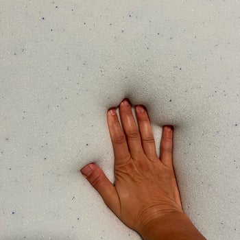 Reviewer placing hand on bed to show the memory foam effect