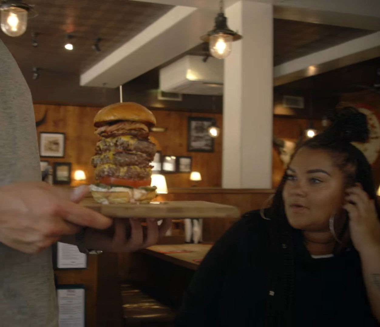 patron stares at a burger that is several stacks high
