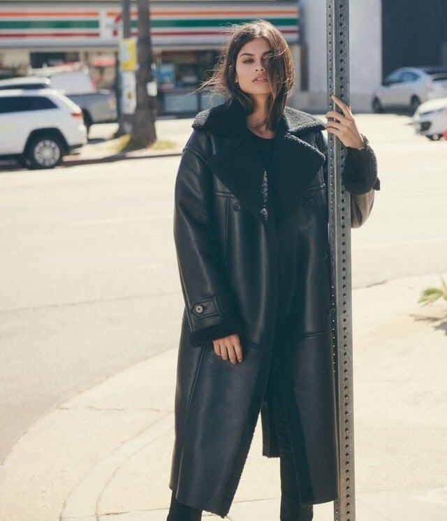 someone wearing the coat outside while holding onto a stop sign pole