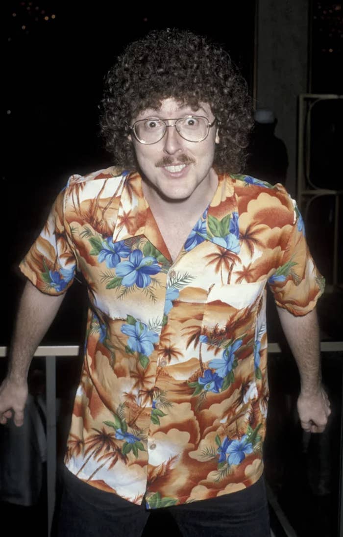 closeup of Weird Al wearing a hawaain shirt, wired glasses, and mustache