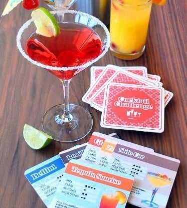 the recipe coasters laid out on a table with some cocktails