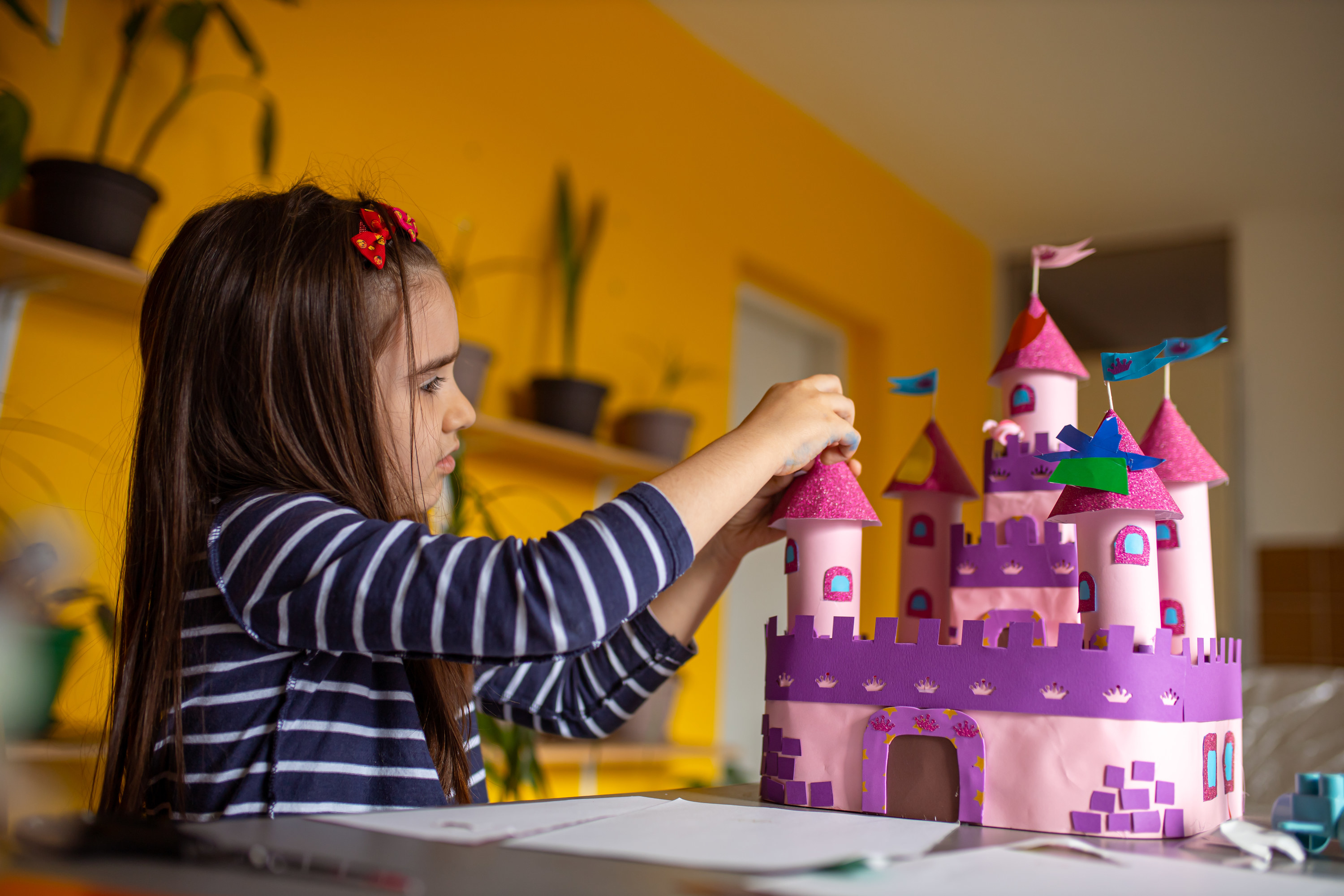 child playing alone with a castle built out of paper