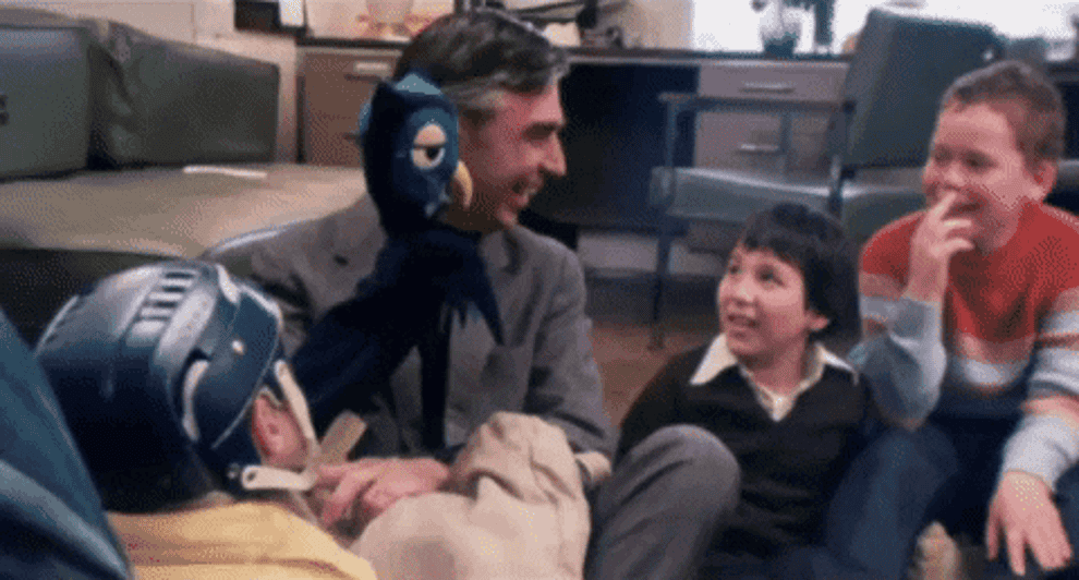 Mr Rogers uses a puppet and laughs with several children