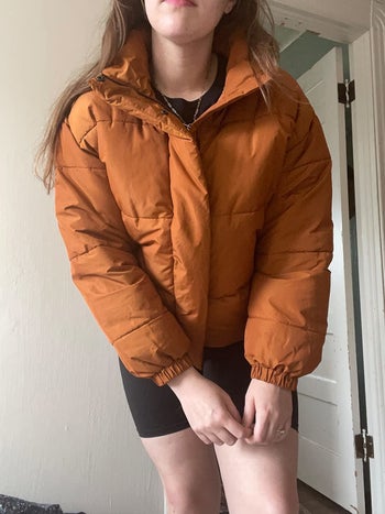 a reviewer wearing the orange puffer jacket