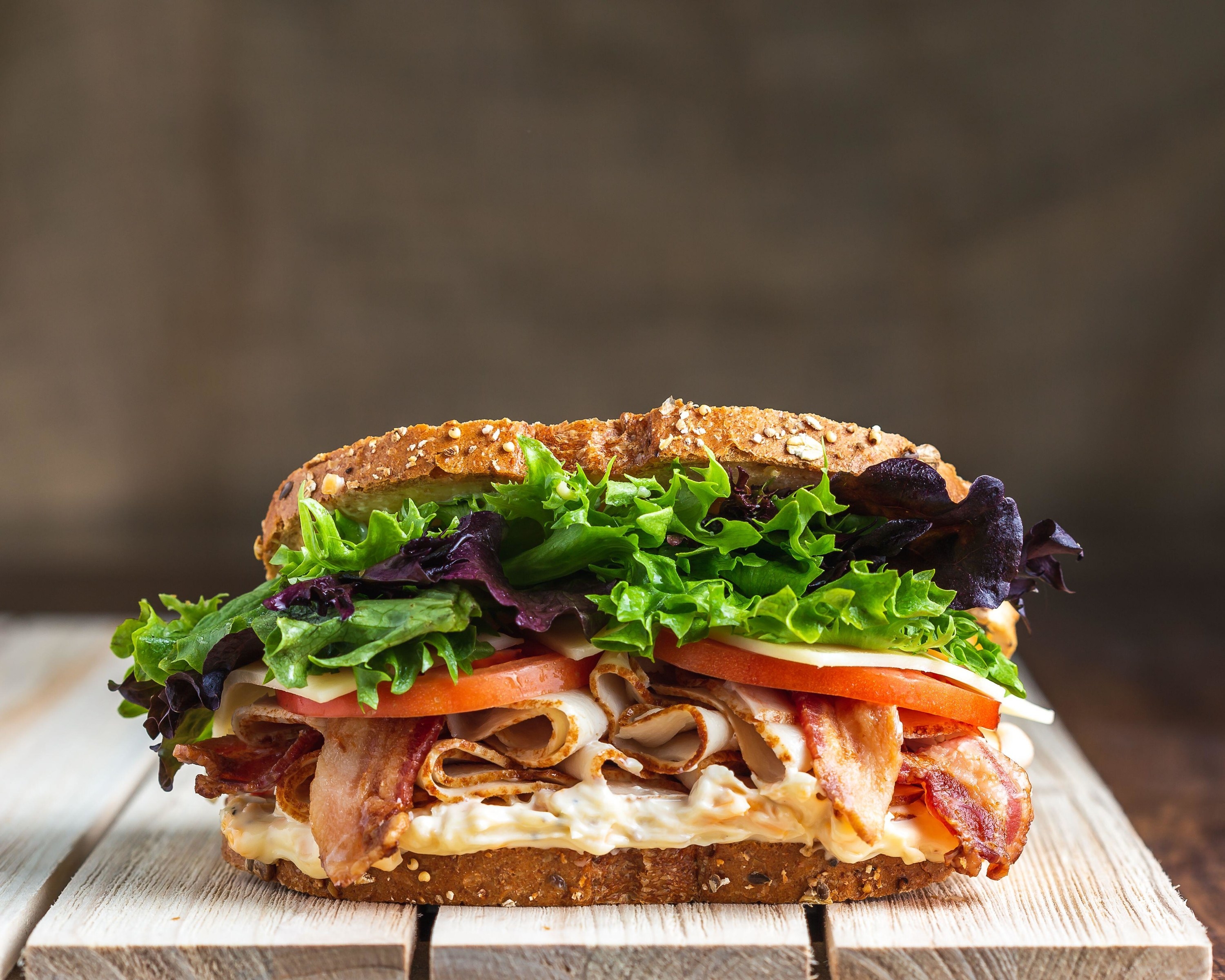 BLT sandwich on wooden surface with linen backdrop