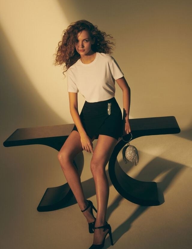 someone sitting on a table wearing the skirt with a t-shirt