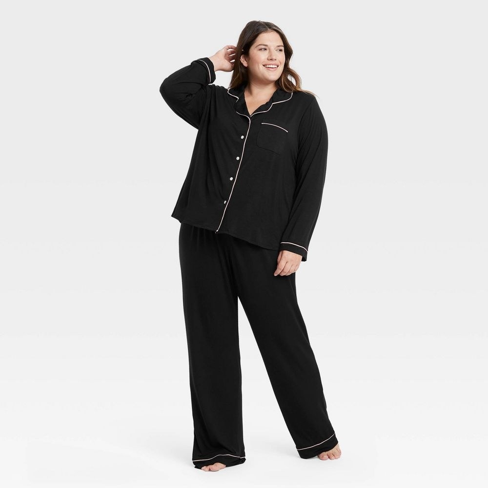 model in black pj set with long sleeves, long pants, and white piping