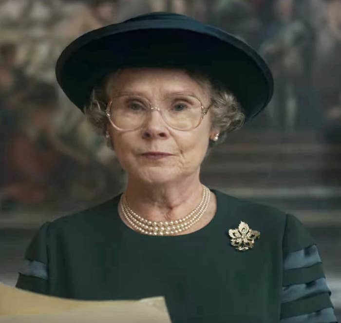 Imelda wearing a brimmed hat, eyeglasses and a three-strand pearl necklace