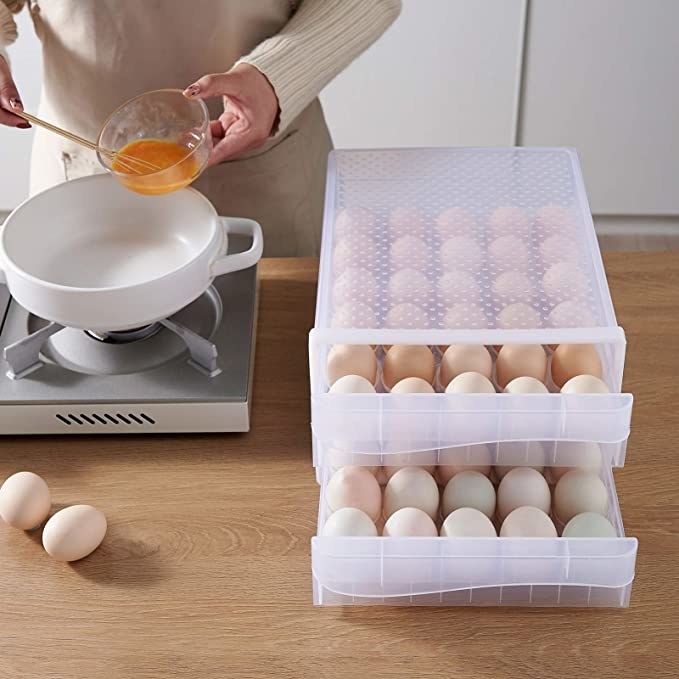 The egg container on a counter beside a person cooking