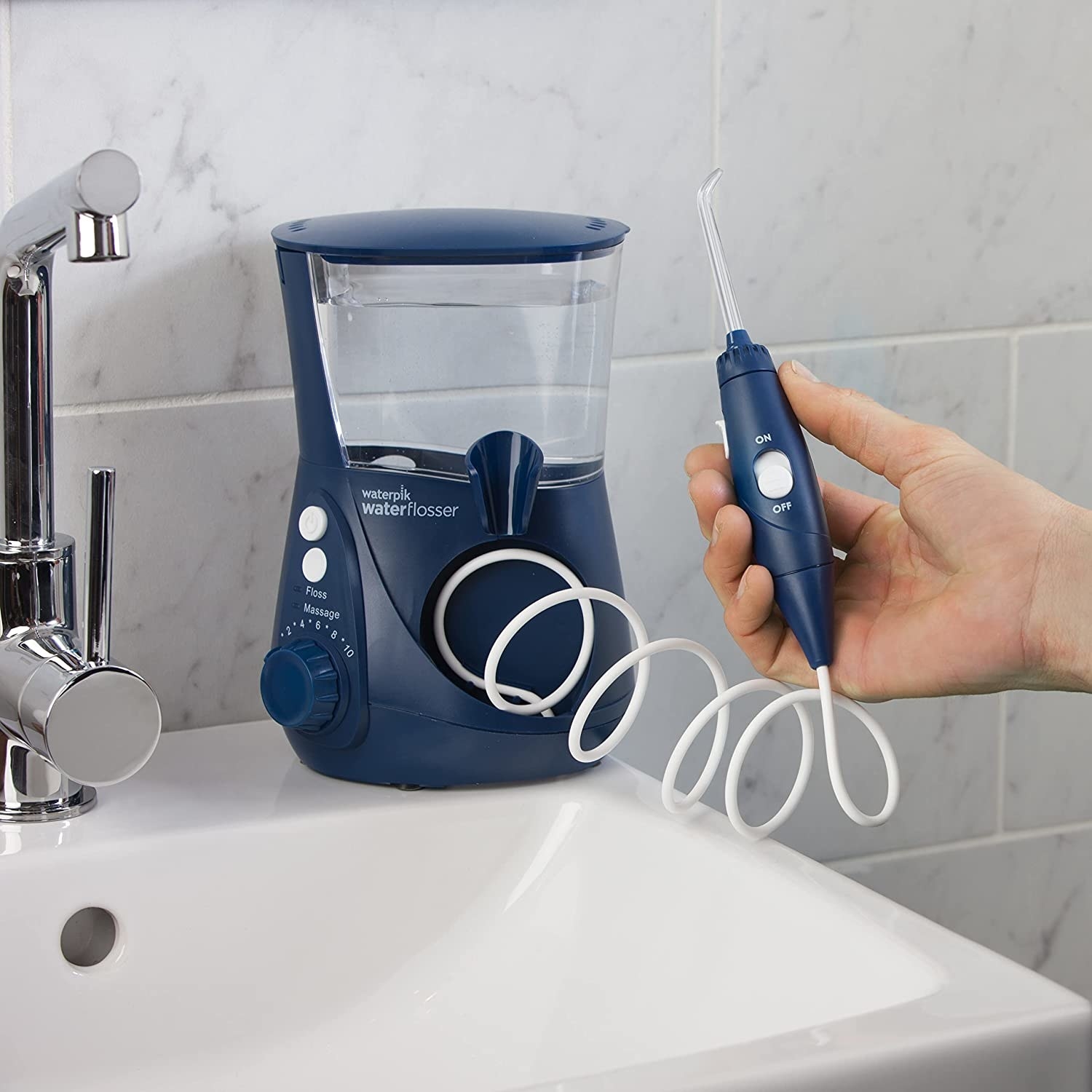 A person holding the waterpik in their hand