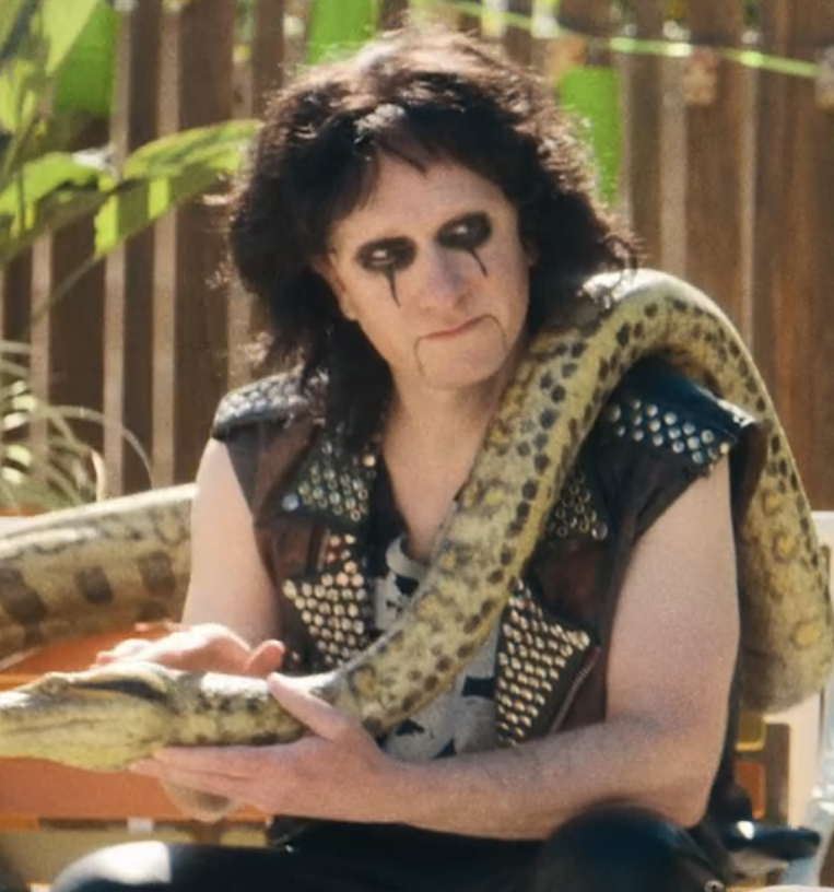 Akiva holding a large snake and wearing heavy eye makeup for his character