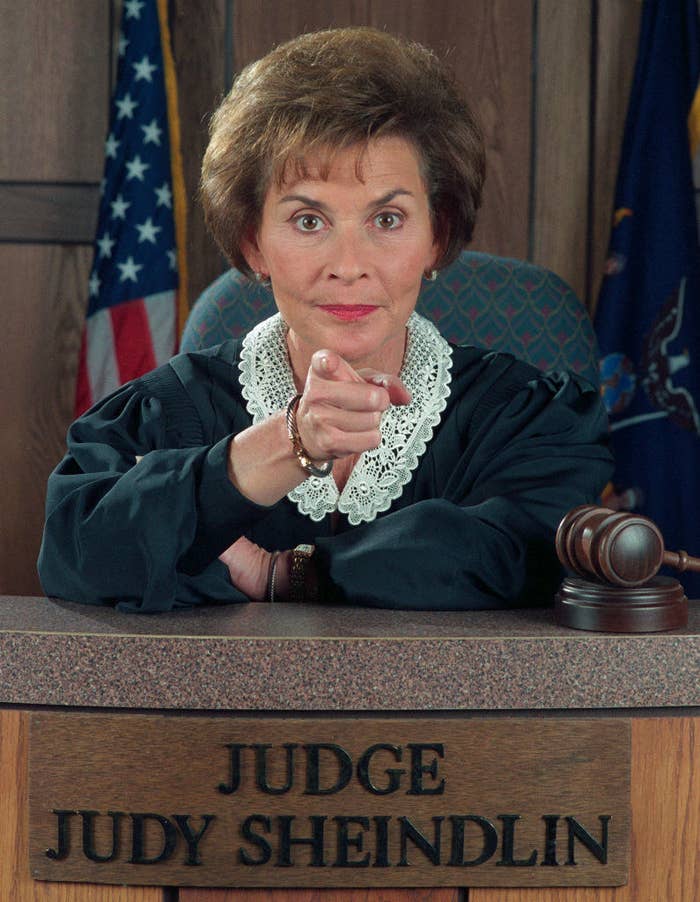 Judge Judy pointing directly at the camera as she sits on the bench