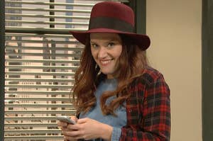 Kate McKinnon smiling while holding a cellphone in an SNL sketch