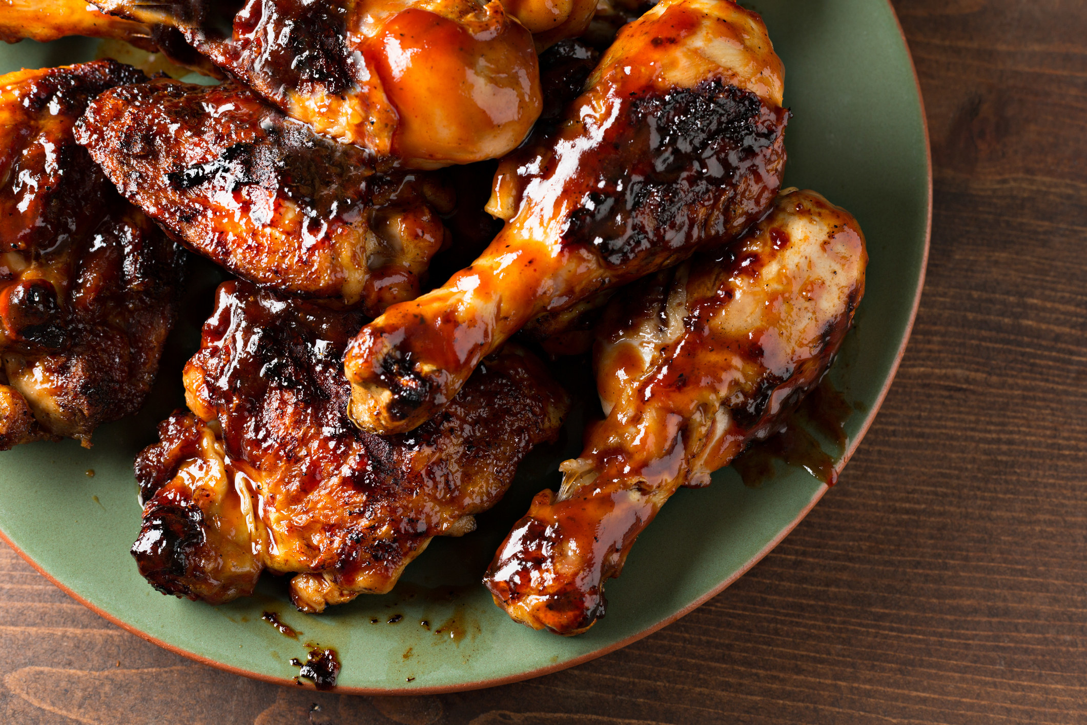 Barbecued chicken drumsticks and thighs on a green platter..