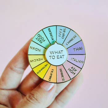 an enamel pin of a colorful wheel with various food options on it and 