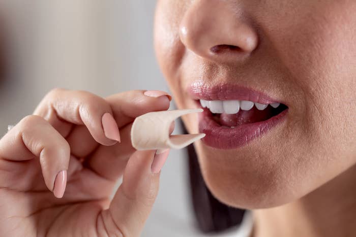 A person putting a piece of gum in their mouth