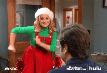 Leslie Knope swinging her arms dressed in a Christmas outfit