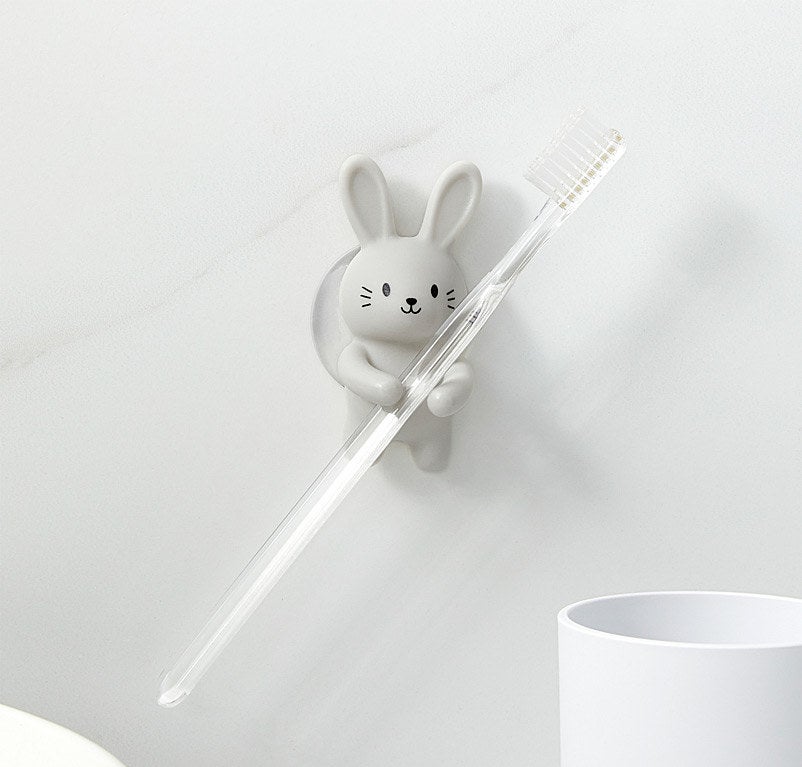 the rabbit toothbrush holder suctioned to the wall while holding a toothbrush