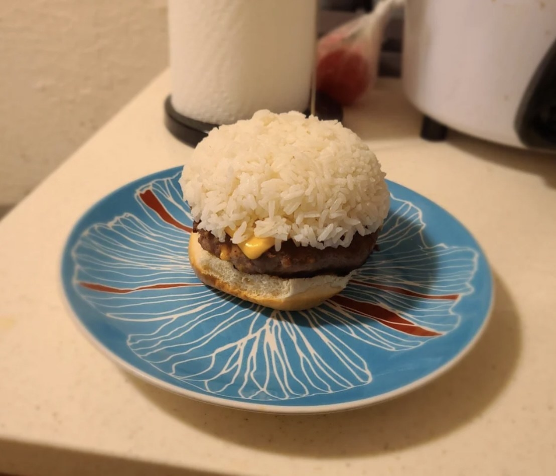 burger with a bun on the bottom but rice on top of the meat