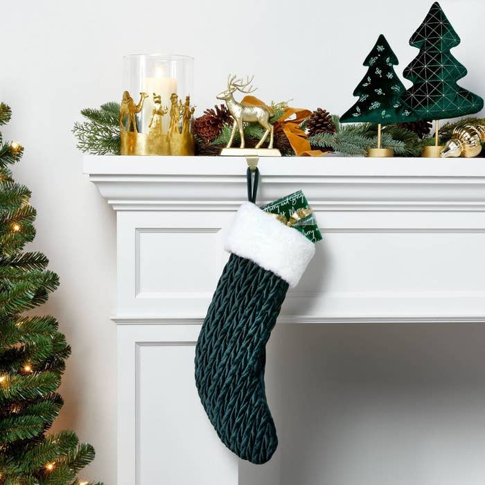 A green stocking hanging on a mantle