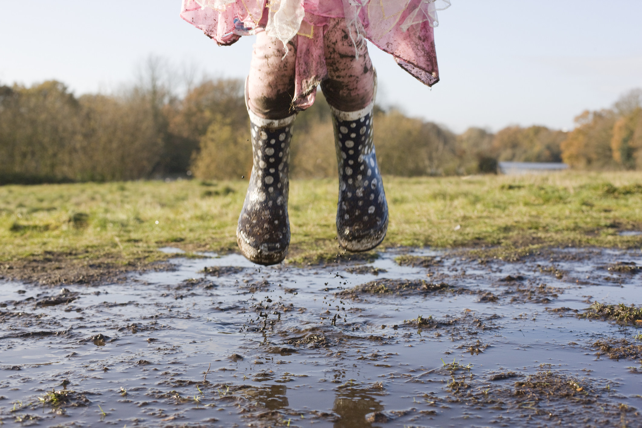 A child jumping in a puddle of mud