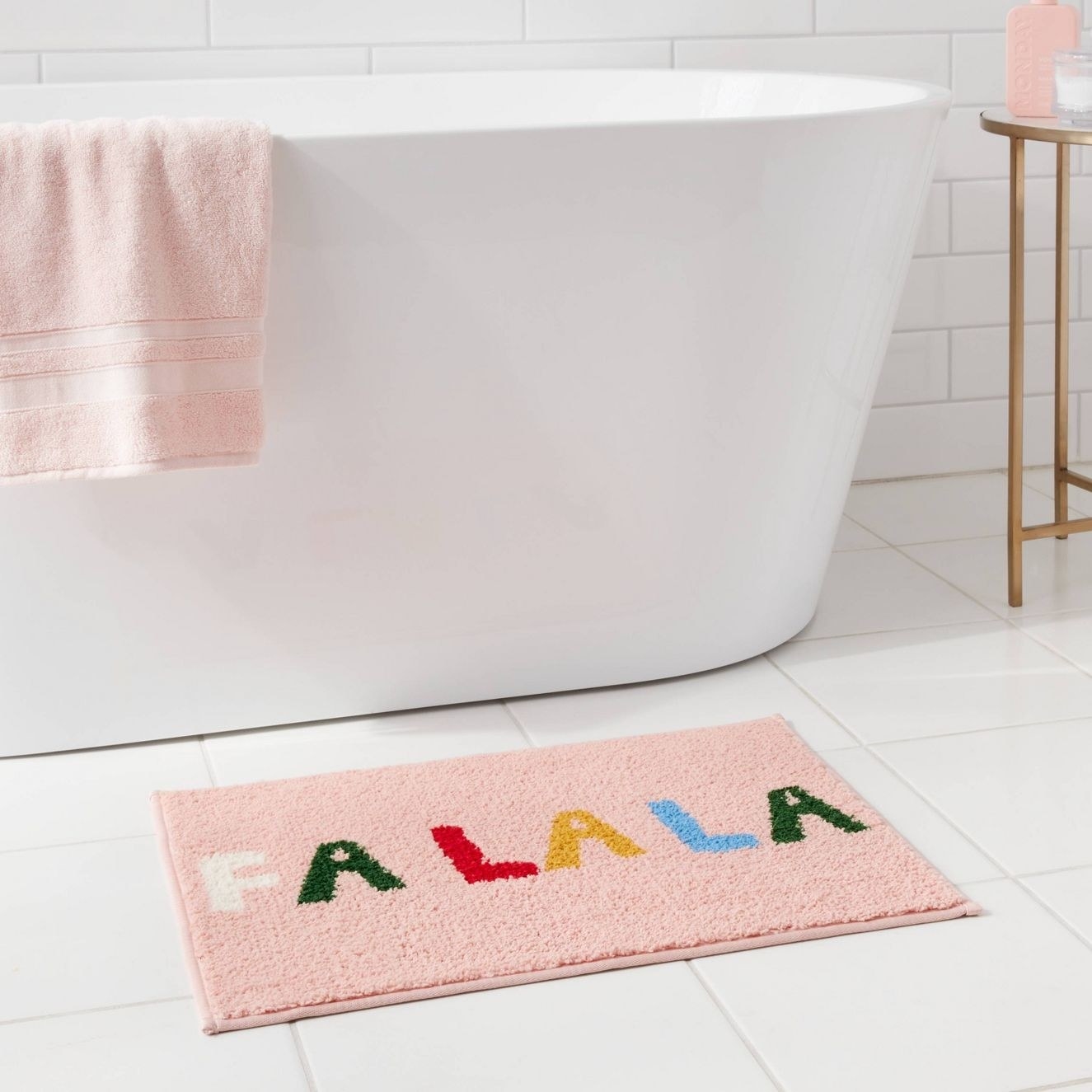 The bath mat that says Fa La La outside a tub