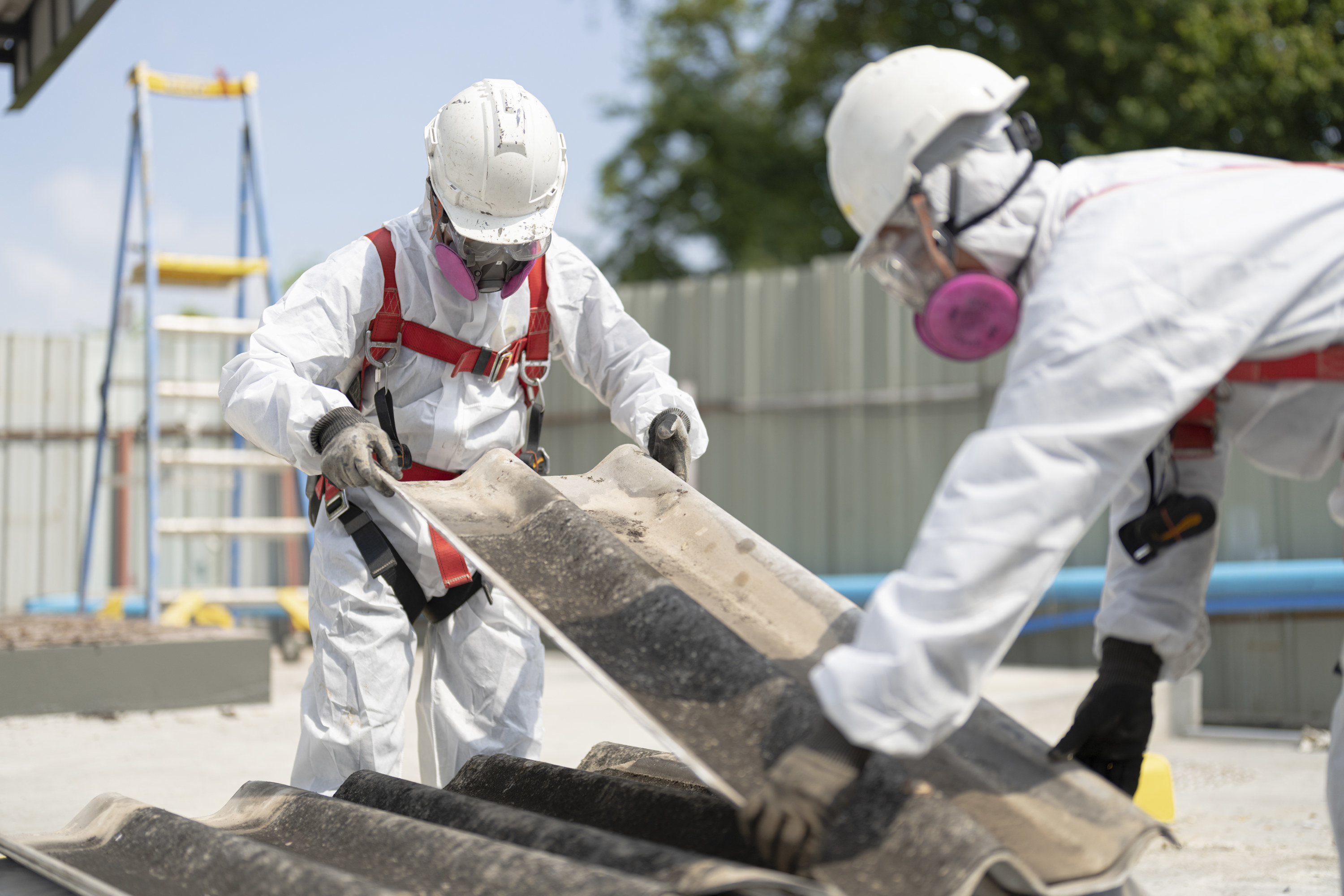 workers in protective gear disposing of asbestos roofing
