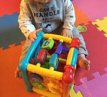 reviewer's photo of their baby playing with the activity cube