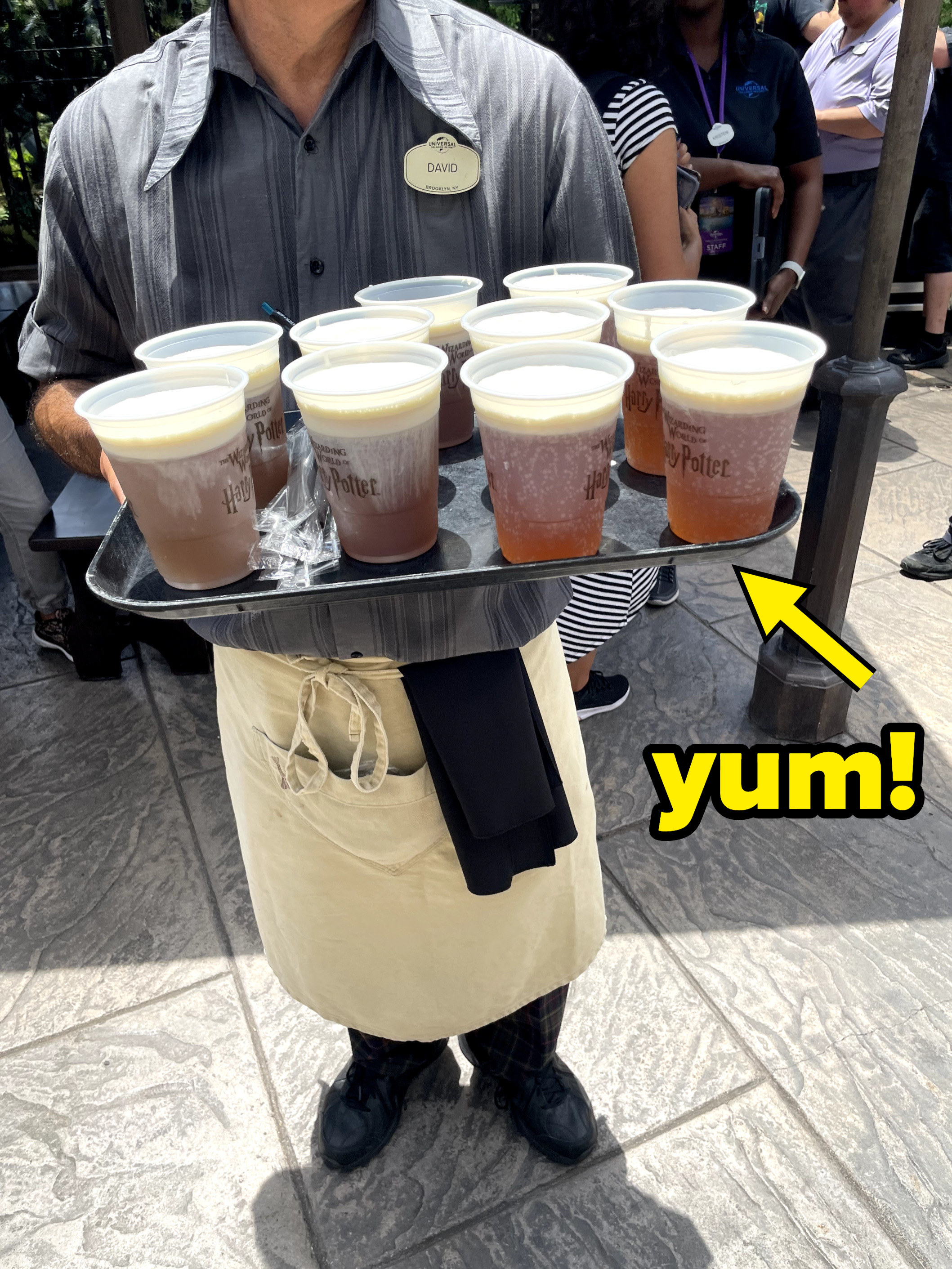 a person holding a tray of butterbeer with the word &quot;Yum!&quot;