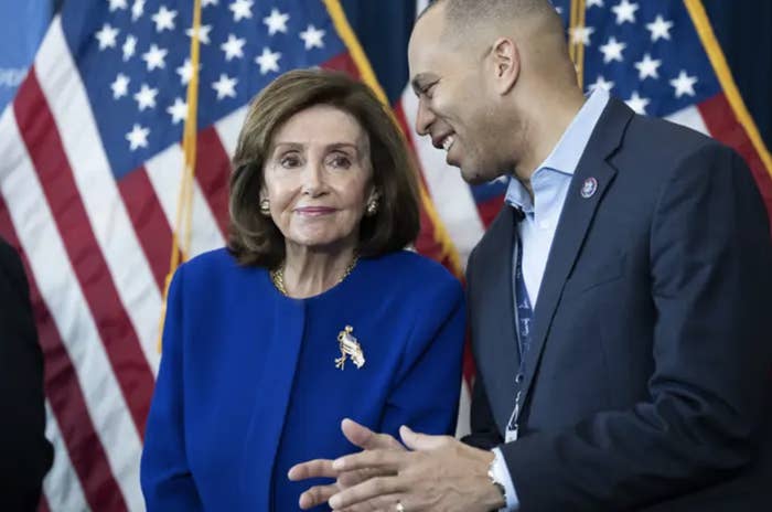 Nancy Pelosi in blue standing next to Hakeem Jeffries in a suit