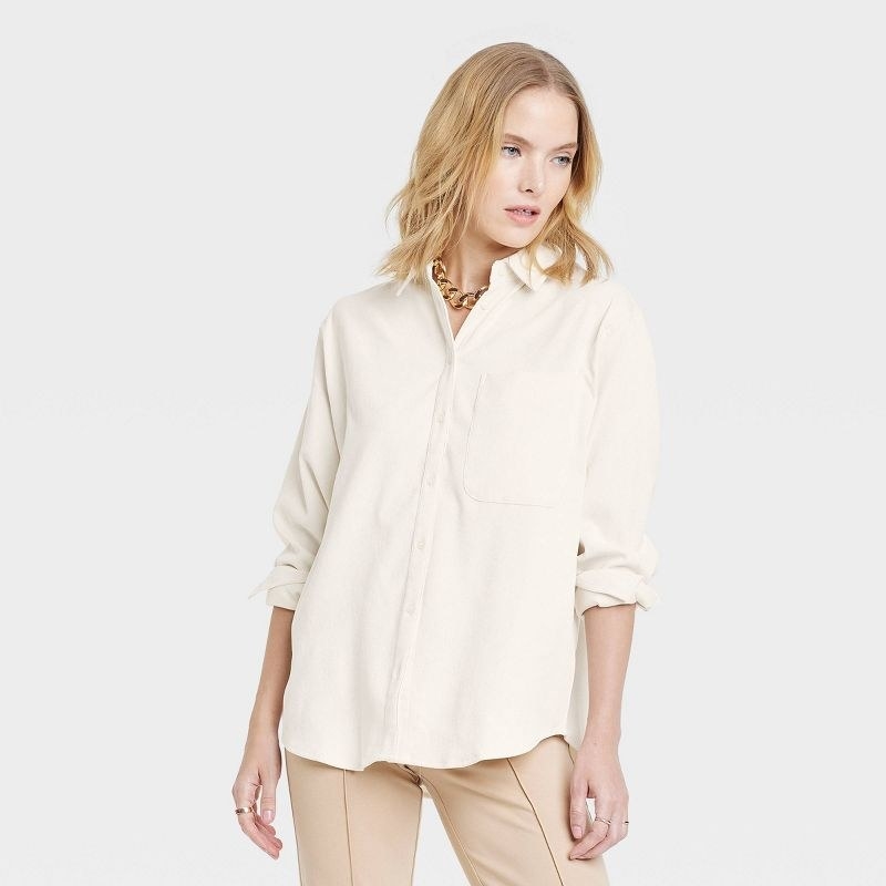 Model wearing cream top and beige pants and gold necklace