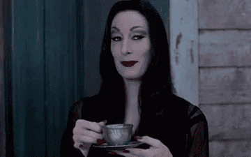 Morticia Addams drinking tea and raising eyebrows with a smirk on her face