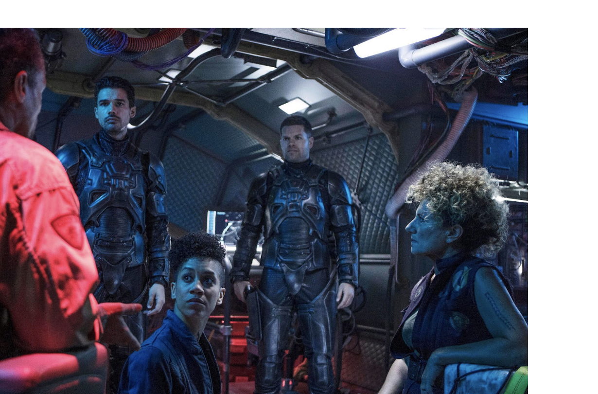 A group of people stand and sit in a spaceship