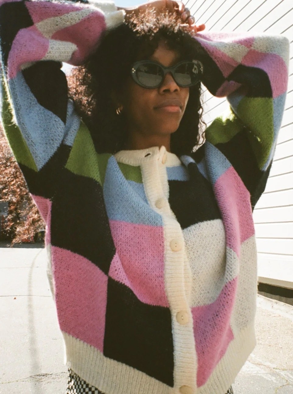 model in black, white, pink blue, and green checkered cardigan