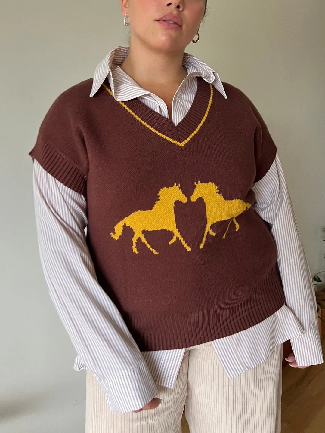 model in brown sweater vest in yellow horses on it