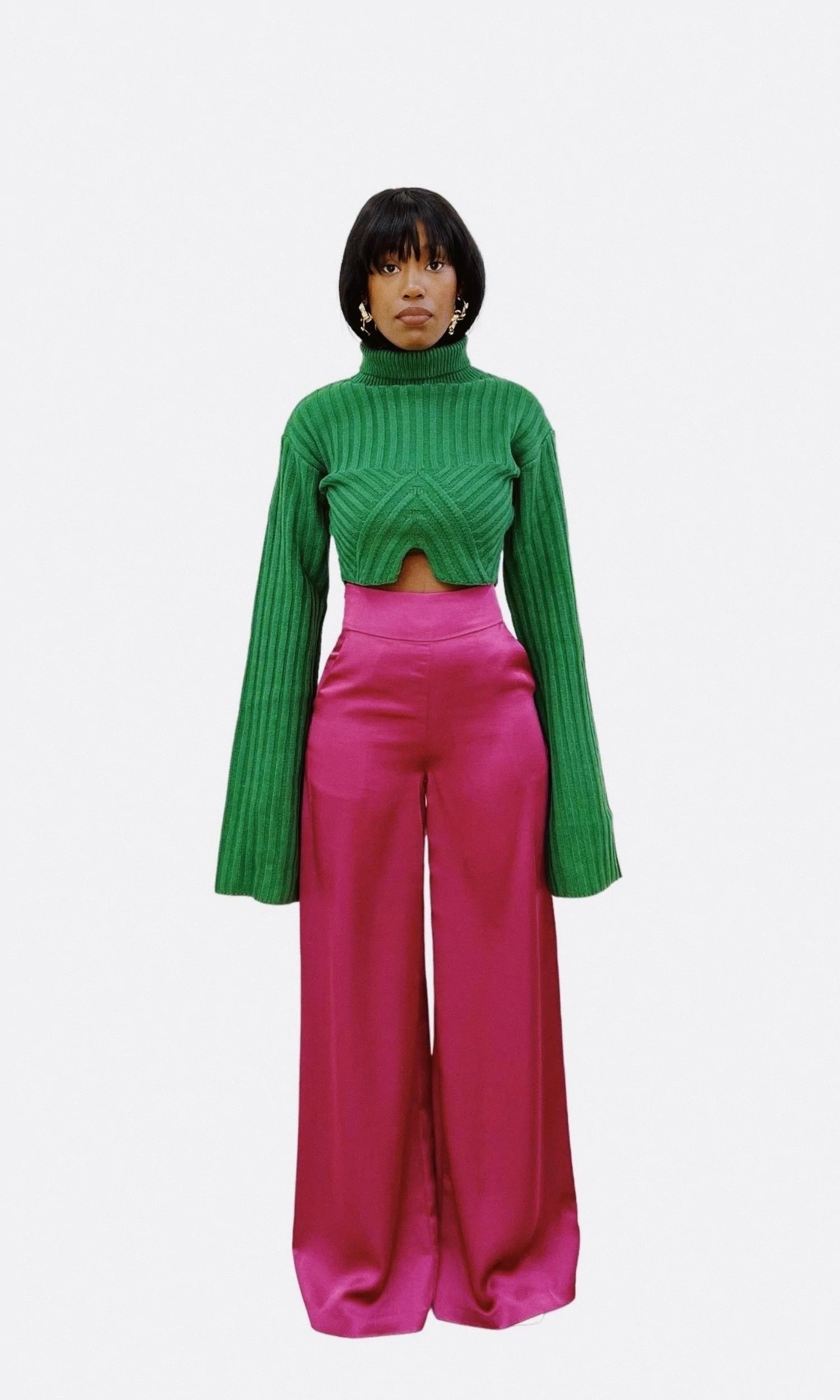 model in green ribbed cardigan with super long wide sleeves, a notched cutout under the chest, and a turtleneck