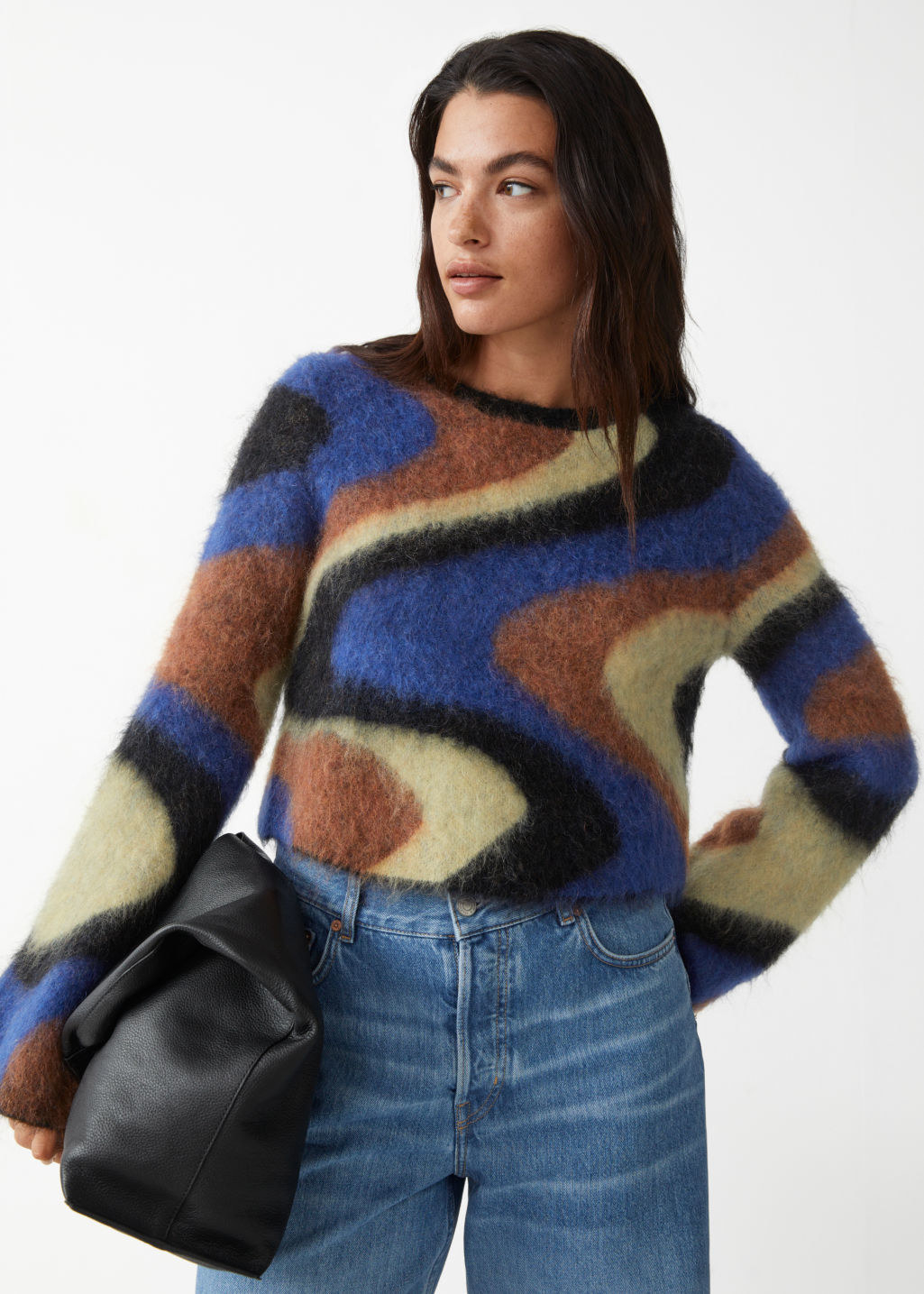 model in crewneck with wide sleeves in a cream, light brown, black, and blue swirl pattern